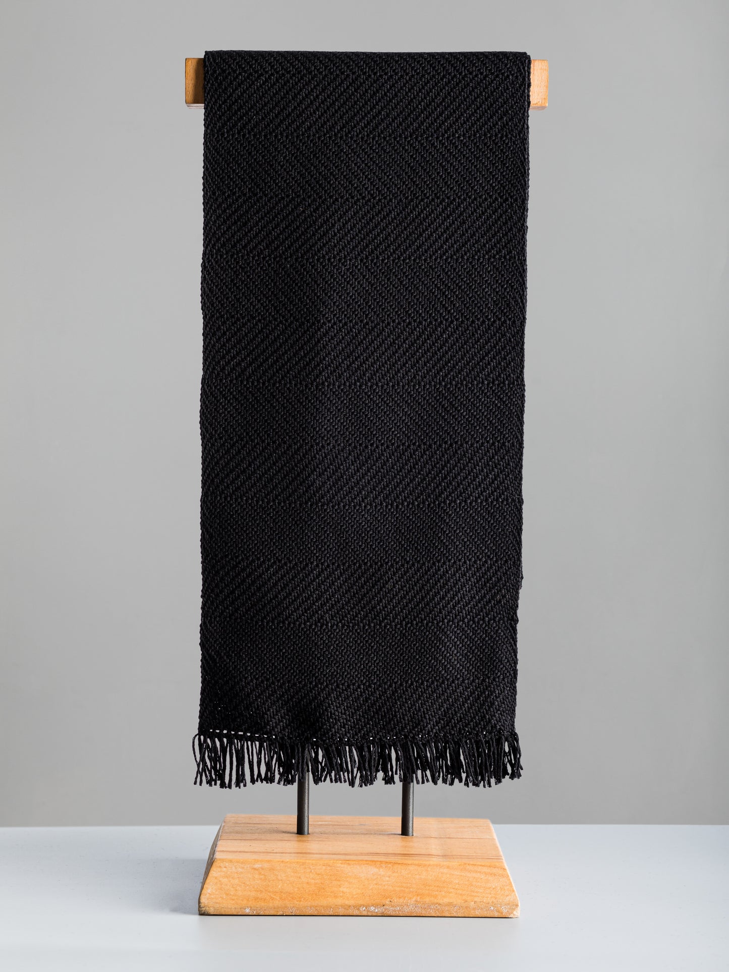 Sciarpa tessuta a mano in pura lana merino, colore nero, su manichino